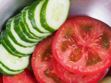 Salatalık ve domatesler tahta bir tahtanın üzerinde daireler çiziyor. sebze kullanımı