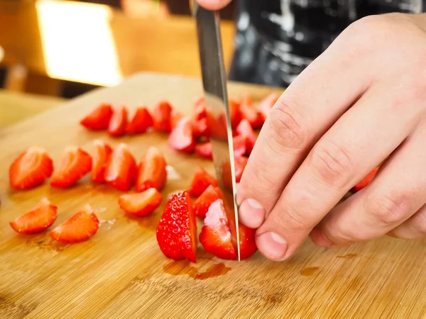 Aşçı ahşap bir tahtada büyük bir çilek keser. Poster. Yazın