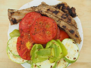 Lezzetli kızarmış sebzeler, tabakta domuz pirzolası, yemekler ızgarada.