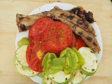 Lezzetli kızarmış sebzeler, tabakta domuz pirzolası, yemekler ızgarada.