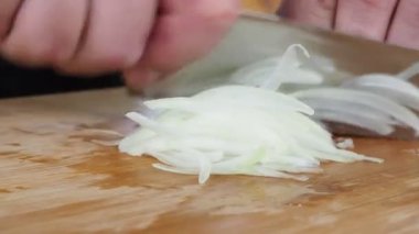 Aşçı ahşap bir tahtada soğan kesiyor. 4K video