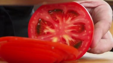 Aşçı ahşap bir 4K videoda lezzetli domatesleri dilimliyor..