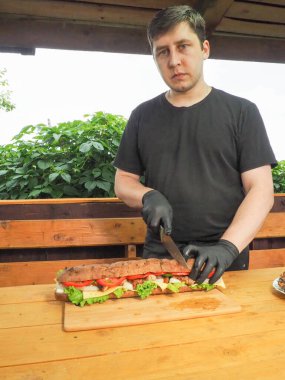 Şef, Fransız ekmeği sandviçi ile şifalı peynir ve et keser.