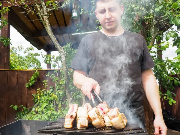 Mladý Muž Vytahuje Steaky Kleštěmi Grilu Talíři Kuchař Vepřové Steaky — Stock fotografie