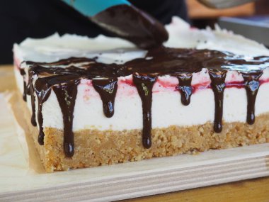 Pasta şefi lezzetli bir pastanın üzerine çikolata döküyor. Çikolata. Tatlının hazırlanması..