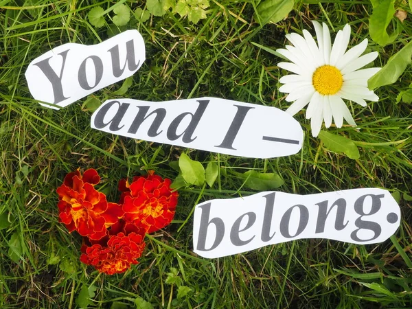 English proverb. an inscription of carved letters on the grass. you and i - belong