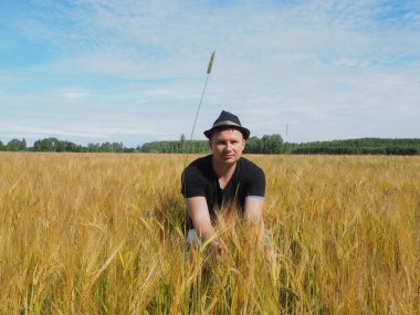 Şapkalı bir adam arpa tarlasında oturur. Hasat. çiftlik alanı.