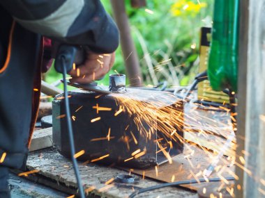 Bir adam metali bir açı öğütücüsüyle idare eder. metalden kıvılcımlar.