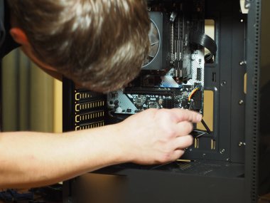 Genç bir adam kişisel bir bilgisayar yapıyor. Atölye. Onarım. bilgisayar durumu.