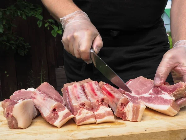 Bir adam bifteğe et kesiyor. Eldivenli el. Kemiklerinde et var.