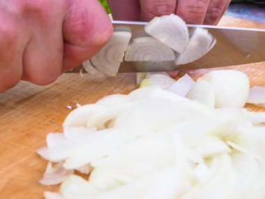 Bıçakla soğan doğramak. Ellerini çerçeveye koy. Tahtada yemek pişirmek.