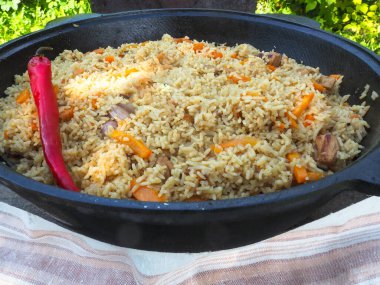 Kırmızı biberli bir kazanda pilav. et ve pirinç.