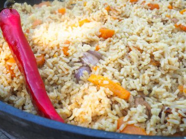 Kırmızı biberli bir kazanda pilav. et ve pirinç.