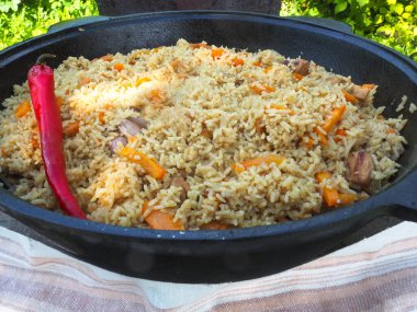 Kırmızı biberli bir kazanda pilav. et ve pirinç.