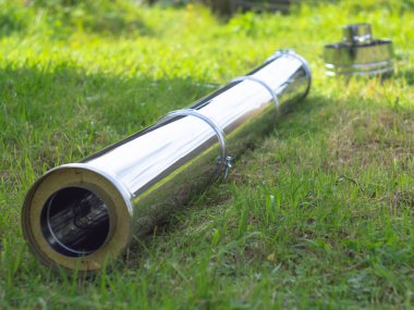 Yerdeki fırınlar için boru hatlarının montajı. Yeşil çimlerin üzerinde pipo sandviç.