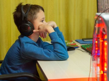 Bilgisayarın başındaki kulaklıklı çocuk. Online çalışma. Dersleri dinliyor. eğitim.