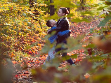 Oğlu parkta annesine sarılıyor. Çocukların ailelerine olan sevgisi. Parkta yürü. Aile mutluluğu