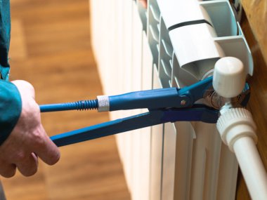 Adam somunu radyatöre sıkıyor. Isıtma pillerinin kurulumu. Tesisatçı işi..