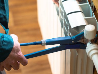 Adam somunu radyatöre sıkıyor. Isıtma pillerinin kurulumu. Tesisatçı işi..