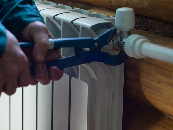 the man tightens the nut on the radiator. installation of heating batteries. plumber\'s job.
