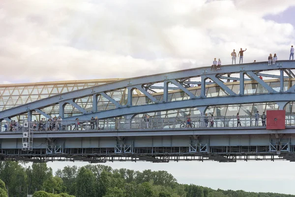 People on the metal bridge waving their hands over the Moscow river.