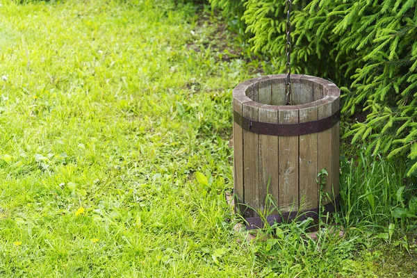 Old wooden bucket on the grass. Rural area, bucket with chain.