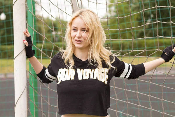 Güzel bir sarışın futbol net holding ve oyun sırasında gülümseyen.