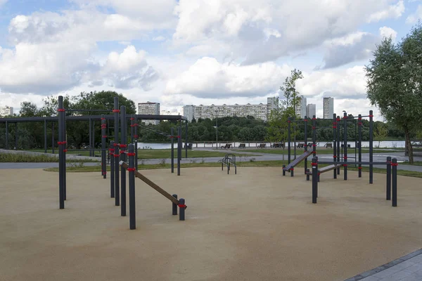 Playground with horizontal bars in the open air on the background of the river and houses.