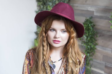 Güzel kız Riga kıvırcık saçlı ve başında bir şapka. Beyaz ve ahşap duvarlar ile Studio.