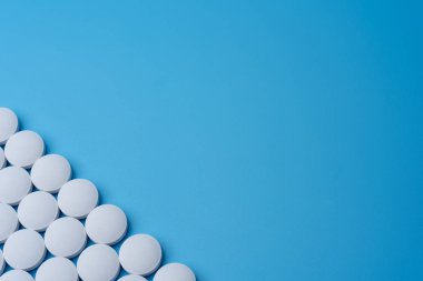 Alt sol köşede mavi bir arka plan üzerinde beyaz tıp hapları. İlaç Laboratuvar.