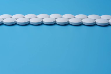 Orta mavi bir arka plan üzerinde beyaz tıp hapları. İlaç Laboratuvar.