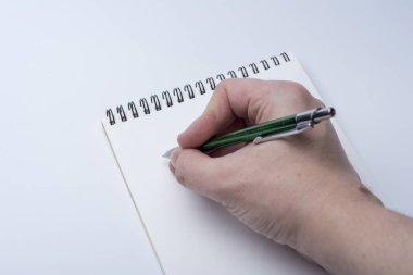 Bir defter ve bir kalem beyaz bir arka planda tutan bir adam elinde. Bellek için Not Defteri'ne yazma.