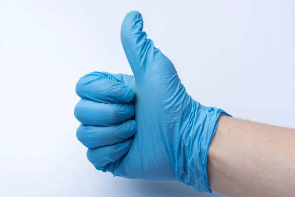 The gloved hand shows the thumbs up. The blue medical glove on the doctor's hand.