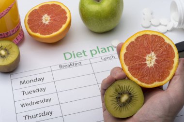 Bir greyfurt ve kivi bir diyet planı üzerinde tutan el. Sağlıklı beslenme kavramı.