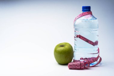 Bir şişe maden suyu ile bir santimetre ve bir elma. Sağlıklı beslenme ve fitness kavramı.