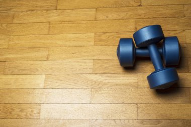 Mavi plastik dambıl, kahverengi ahşap zemin üzerinde. Sağlıklı bir yaşam tarzı, fitness kavramı.