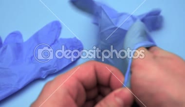 Doktor işlemi önce mavi bir arka plan üzerinde lateks eldiven giyer