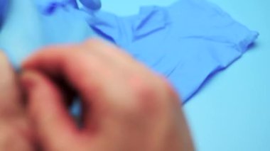 Doktor işlemi önce mavi bir arka plan üzerinde lateks eldiven giyer