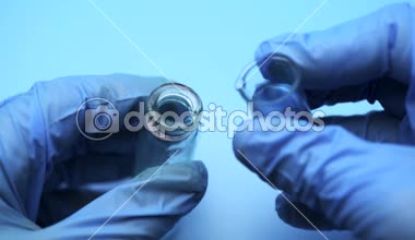 Lateks eldiven eller doktor mavi bir şişeye başka bir sıvı dökülür. Kimyasal araştırma laboratuvarı.