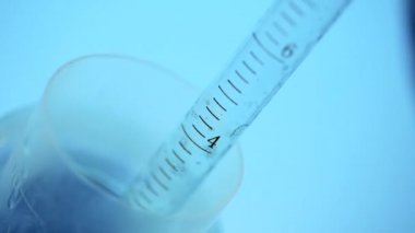Laboratuvarda bir bilim adamı bir pipet ile tüp bebek mavi renk renkli bir sıvı analiz eder. Araştırma kavramı Biyokimya doğa, ilaç tıp
