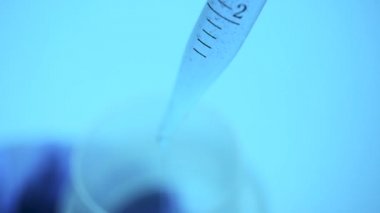 Laboratuvarda bir bilim adamı bir pipet ile tüp bebek mavi renk renkli bir sıvı analiz eder. Araştırma kavramı Biyokimya doğa, ilaç tıp