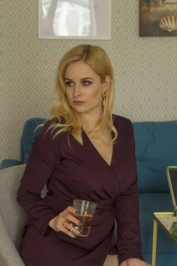 Bir bardak viski ile koyu elbiseli şık kadın.