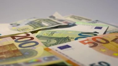 Yüz dolarlık banknotlar ve avrolar masada dönüyor. Kağıt paranın yakın çekim rotasyonu. Paralı arka plan 100 dolarlık banknotlar