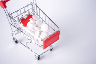 Beyaz arka planda izole edilmiş kapsüllerle dolu bir alışveriş arabası. Büyük miktarlarda ilaç satın alma kavramı.