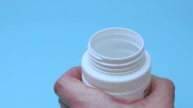 Tabletler mavi arka planda bir kavanoza atılır. İlaç ve bağımlılık kavramı.