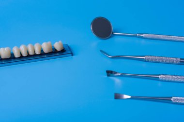 Mavi arka planda diş aletleri olan bir model. Diş sağlığı ve diş sağlığı kavramı.
