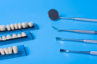 Mavi arka planda diş aletleri olan bir model. Diş sağlığı ve diş sağlığı kavramı.