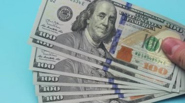 Dolar, vantilatör gibi bir el tarafından tutulur. Nakit para. Benjamin Franklin 'in yüz dolarlık yakın plan fotoğrafı. 100 dolarlık banknotlar ellerinde sallanıyor..