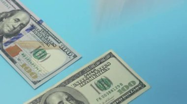 Yüz dolarlık banknotlar mavi masaya düşer. Zenginlik ve refah kavramı.