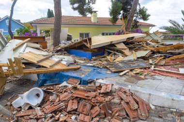 Kırık ahşap ve kiremitler de dahil olmak üzere büyük enkaz yığınları bir yerleşim alanını kaplıyor. Son yenileme çalışmaları, yeşillik ve renkli çiçeklerle çevrili olarak bölgeyi darmadağın etti..